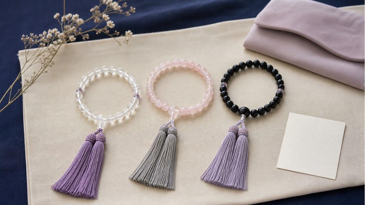 水晶、ローズクォーツ、オニキスの女性用数珠を並べて比較している様子